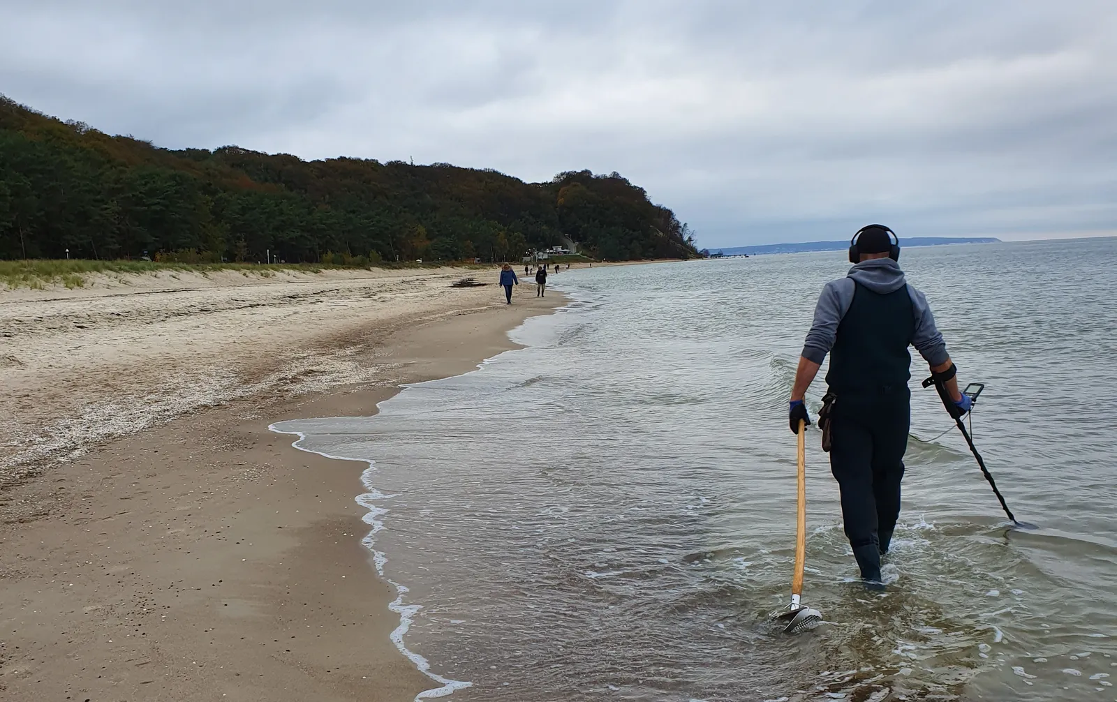 Strandsucher mit Metalldetektor am Spülsaum eines weiten Ostseestrandes